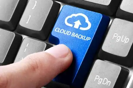 Blue key with cloud backup icon on a computer keyboard.