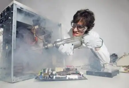 Technician repairing computer with smoke and tools in a workshop.