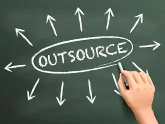 Hand drawing 'Outsource' with arrows on chalkboard for IT services.