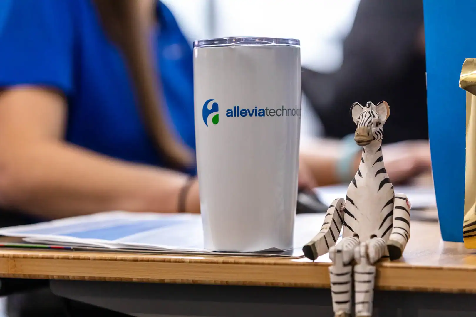 Allevia Technology tumbler with zebra figurine on desk in office setting.