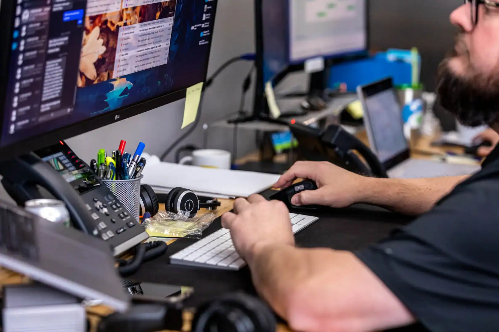 IT technician working on multiple monitors in an office setting.