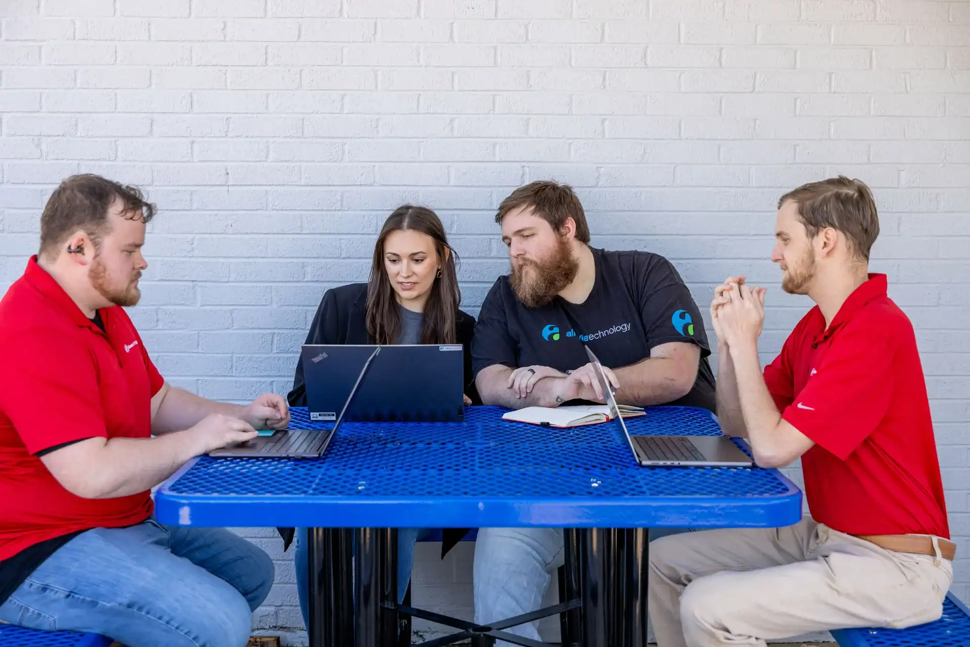 Team of four collaborating on cybersecurity project at a blue table.