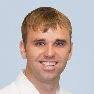 Close-up of a smiling young man with short light brown hair.