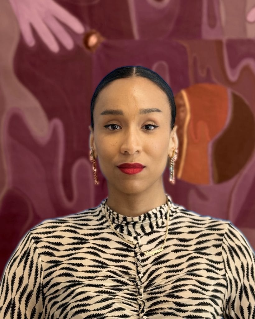 Confident woman in patterned blouse with colorful abstract background.