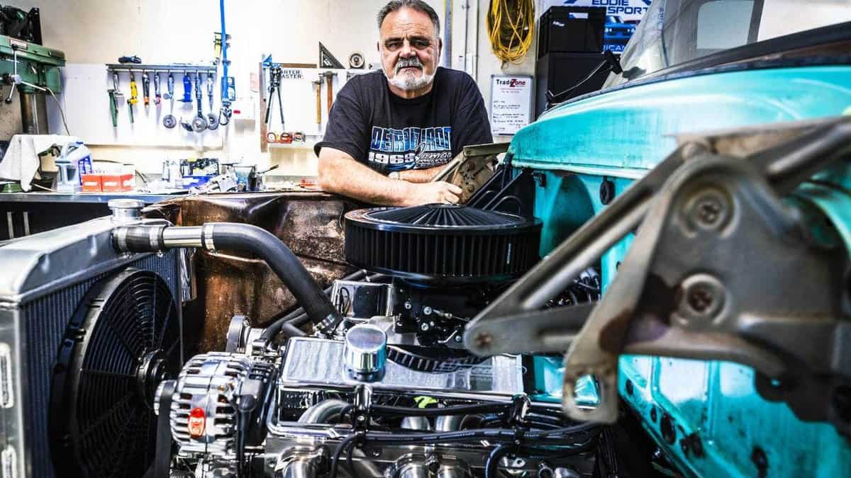 Vintage car restoration in workshop with classic engine and mechanic.