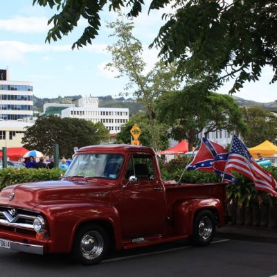 Classic red vintage American pickup truck with flags at Americarna event in New Zealand.