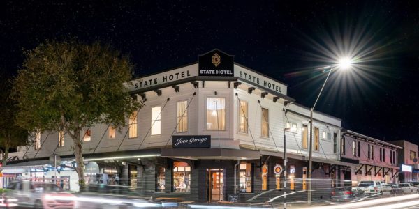 Prime nighttime shot of the historic Americarna hotel with vibrant street activity, showcasing classic American car culture and lively local atmosphere.