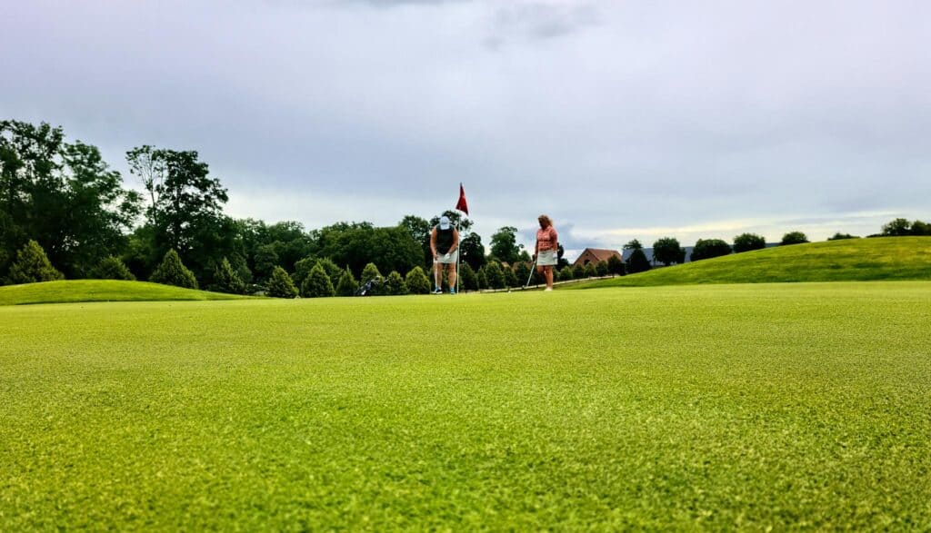Two women enjoy a game of golf on a lush course in Skåne län, Sweden.