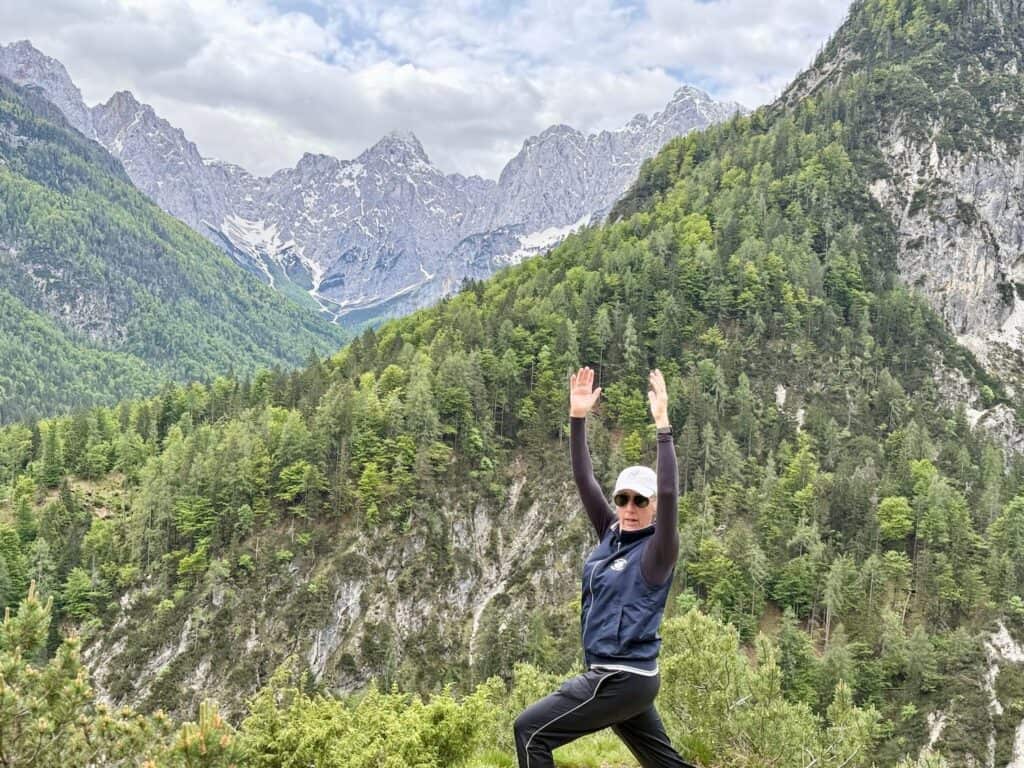 a woman standing on a rock with her arms raised in the air