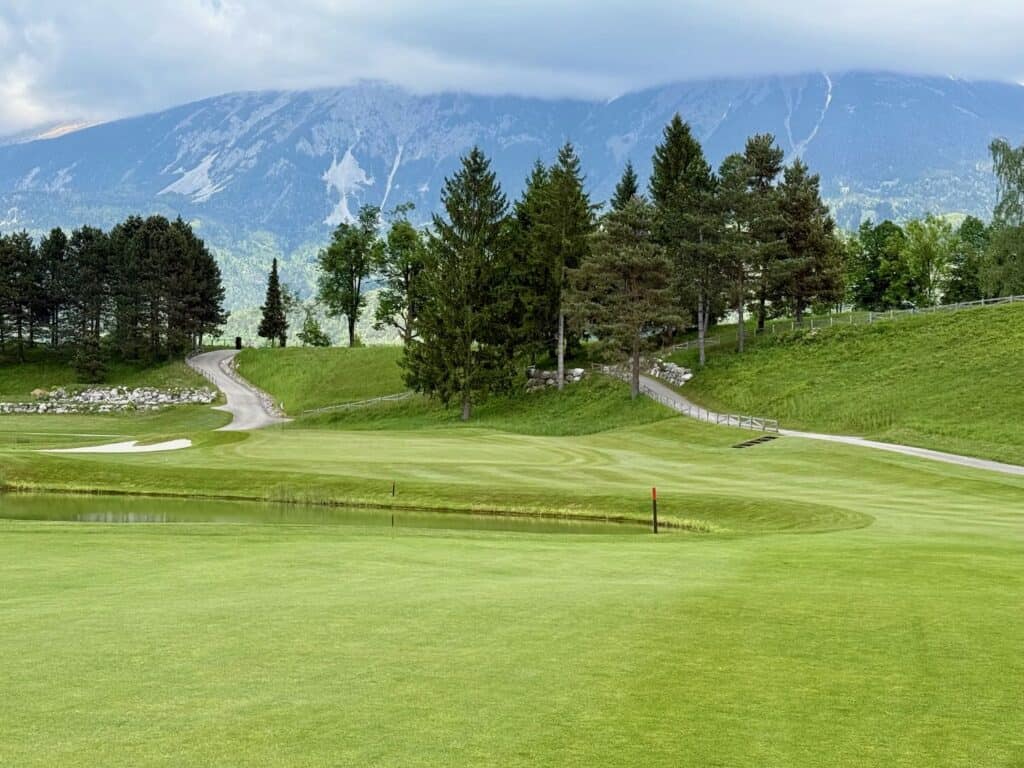 a golf course with trees and mountains in the background