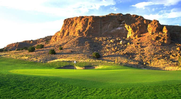 Green golf course with rocky backdrop