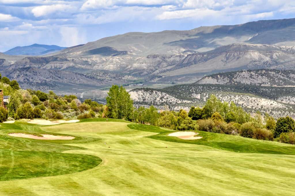 Scenic golf course with mountains in the background and lush greenery.