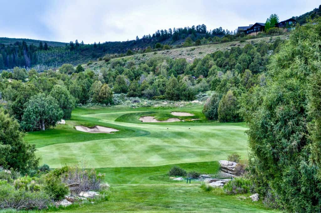 Scenic golf course surrounded by lush greenery and rolling hills.