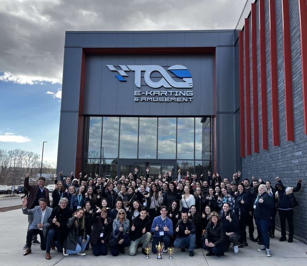 Vibrante groupe de participants lors d'un événement de karting et amusement, devant le centre TGC E-Karting & Amusement, rassemblement d'entreprise convivial.
