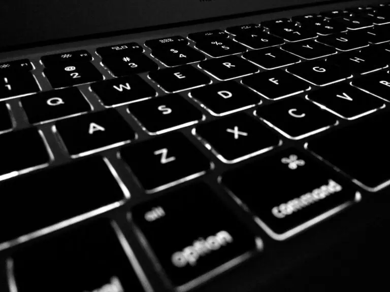 Clavier d'ordinateur rétroéclairé en noir et blanc, mettant en valeur les touches illuminées, idéal pour le travail ou la programmation.