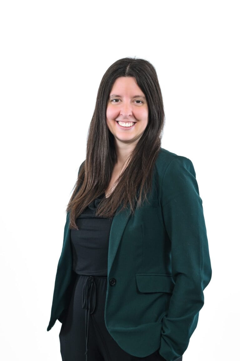 Une photo professionnelle d'Amyot Gelinas, nouvelle associée, portant un blazer vert foncé et un haut noir, souriante, dans un contexte d'affaires.