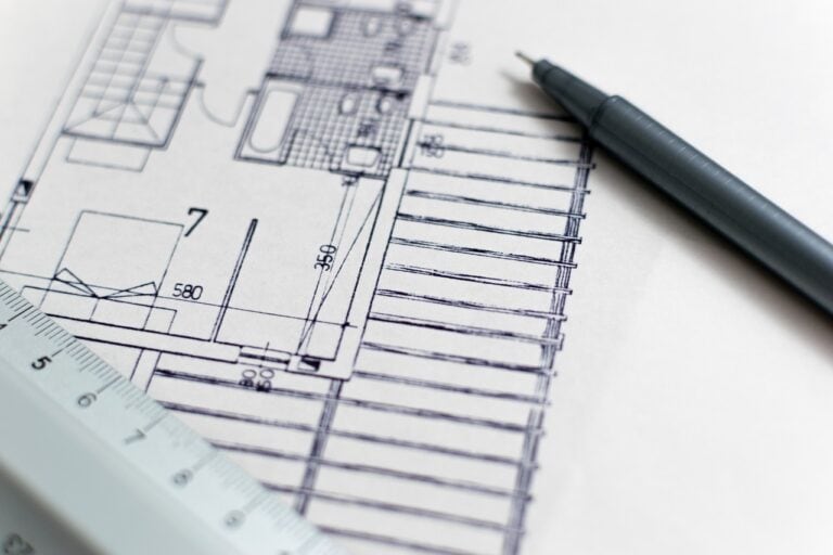 Détail d'un plan architectural avec règle et stylo, illustrant la conception d'une première maison dans le contexte de la bonification du remboursement de la TPS/TVH.