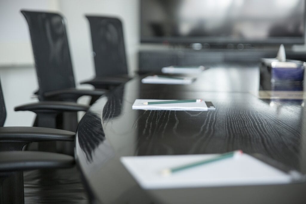 A modern meeting room with a large table, ergonomic chairs and documents for discussing resolutions.
