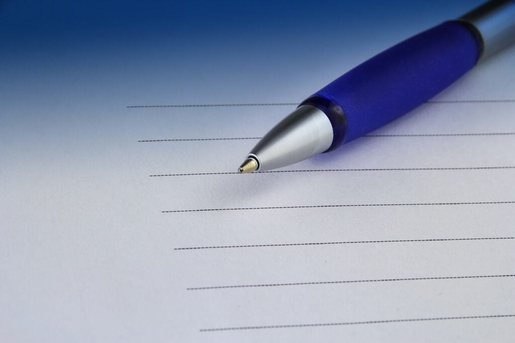 Stylo bleu sur une feuille blanche avec lignes, illustrant la planification et la gestion des procédures RH pour des relations de travail harmonieuses.