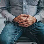 person holding their stomach looking unwell sitting doctor39s office