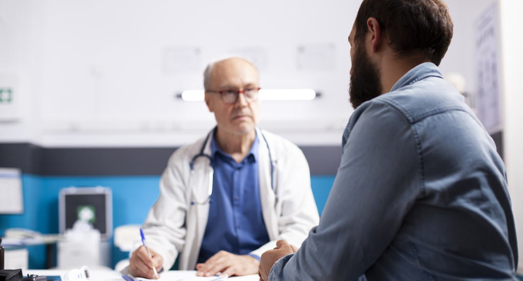 Urologo che spiega a paziente durante visita medica a Palermo.
