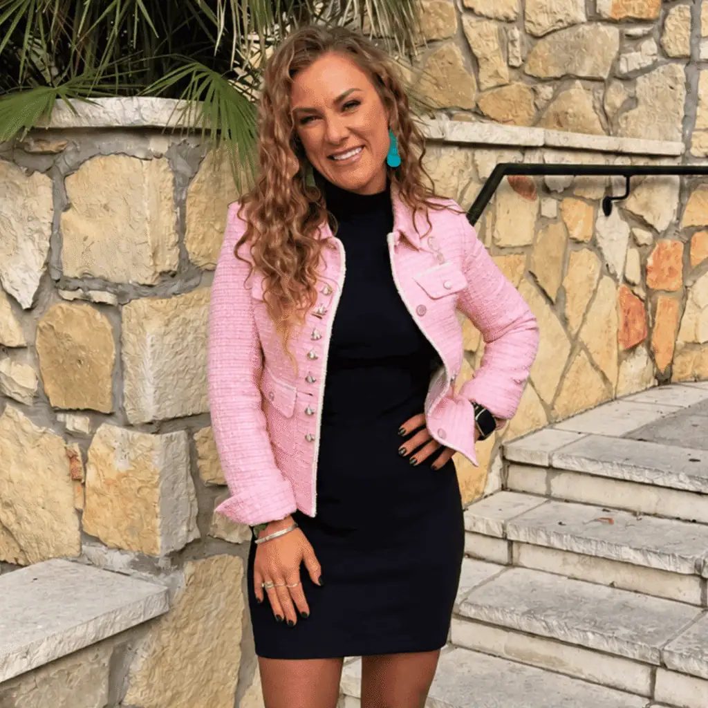 Tricia Phillips standing outdoors in a pink jacket and black dress