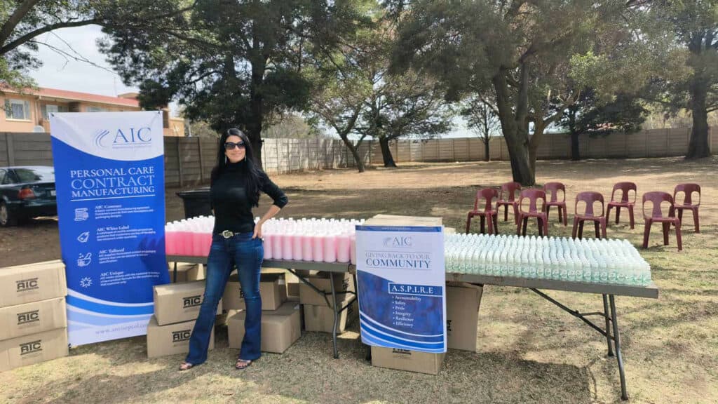 A woman standing next to tables with bottles of antiseptol products at an outdoor event.