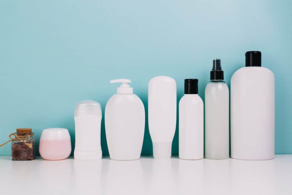 Assorted white skincare bottles and jars on a light blue background.