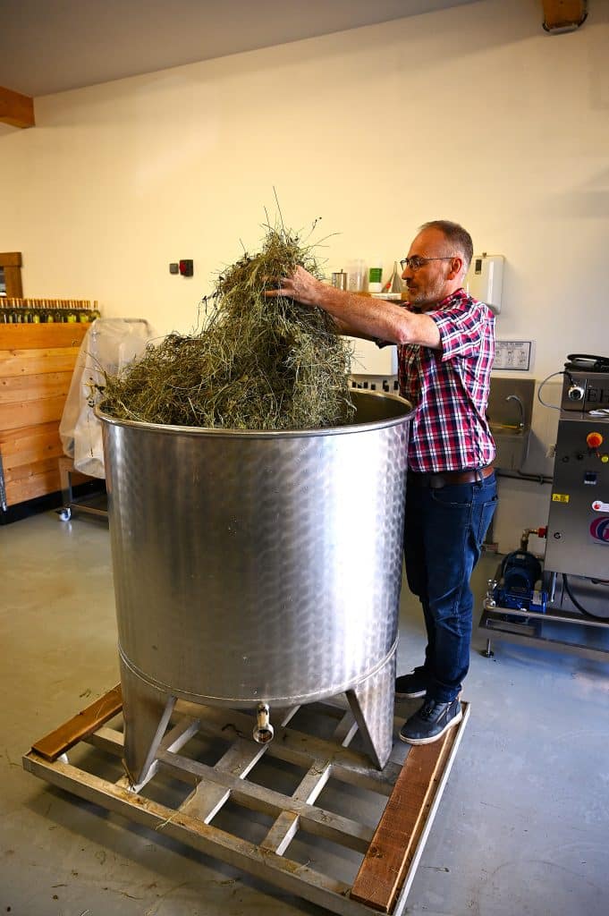 Photo d'un homme préparant des herbes pour apéritifs insolites dans un grand récipient en inox.