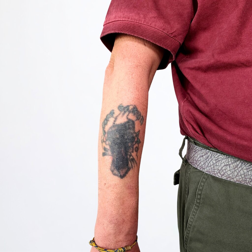 Verblasstes, dunkles altes Tattoo am Unterarm vor einem professionellen Cover-Up.