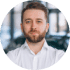 A man with a beard wearing a white shirt, looking forward.