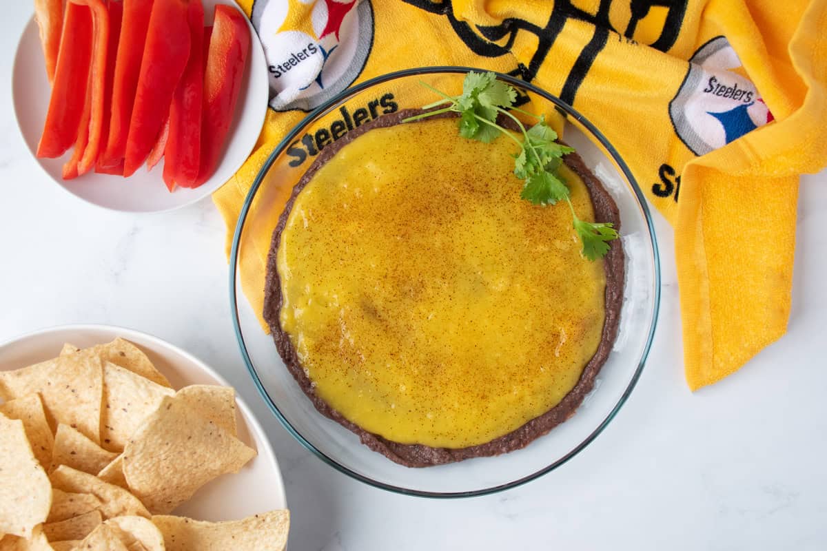 Dish with black bean dip and mango puree layered, garnished with fresh cilantro.