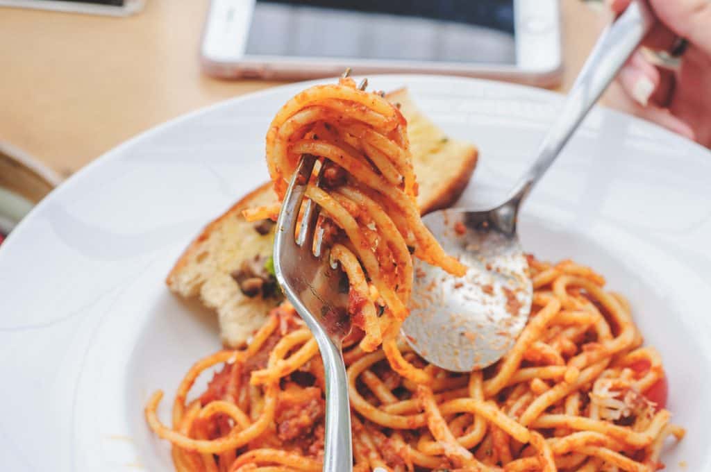 bowl of spaghetti with marinara sauce and utensils.