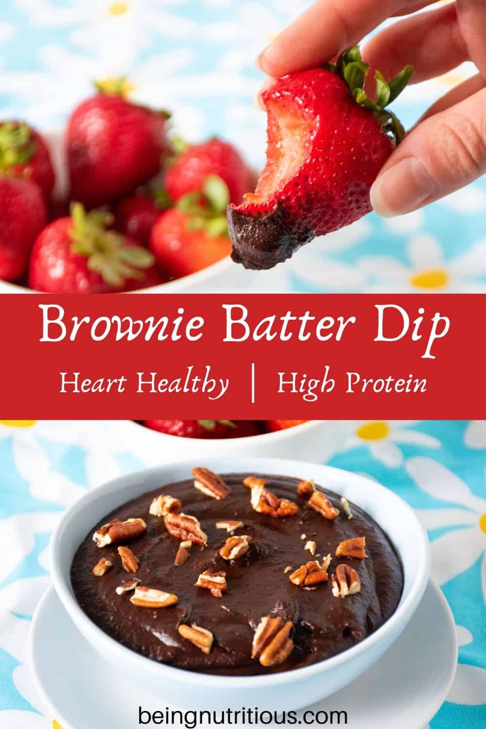 Brownie batter dip in a bowl with a bowl of strawberries behind. A hand holding a strawberry with dip on it and a bite taken out in the foreground.