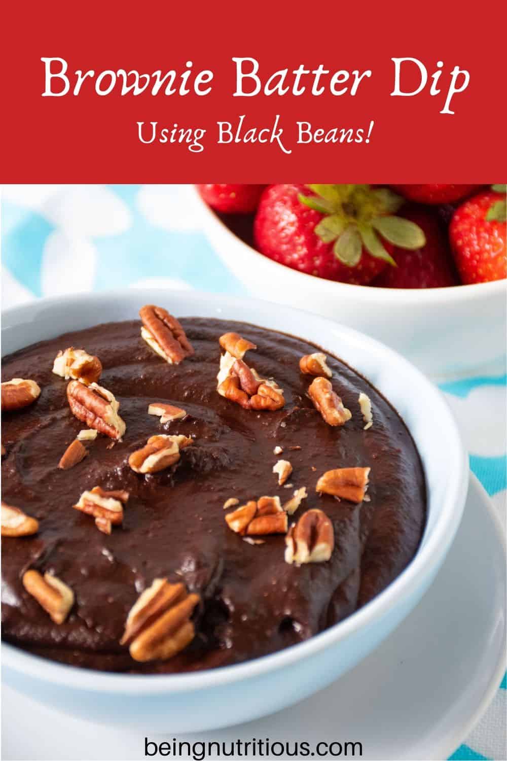Close up of brownie batter in a bowl with pecan pieces on top.