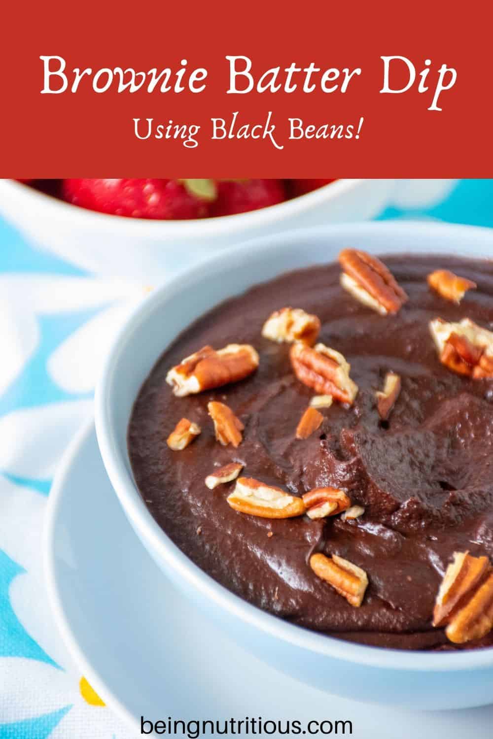 Close up of brownie batter in a bowl with pecan pieces on top.