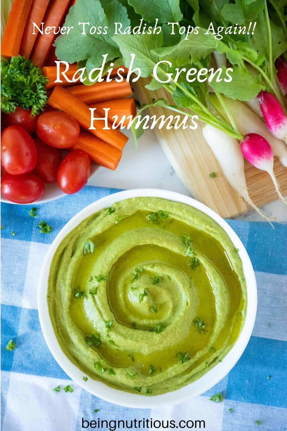 Overhead view of radish greens hummus in a white bowl, with a variety of vegetables around the top of the picture