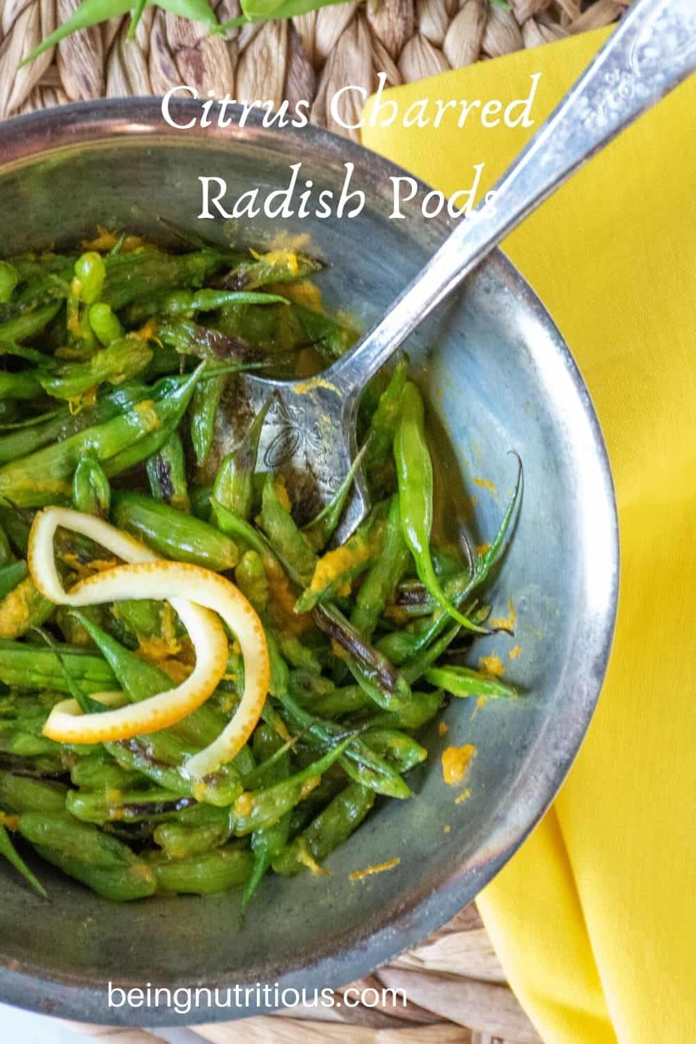 Overhead shot of charred radish pods and orange peel garnish in a silver bowl with a silver fork and text overlay: "Citrus Charred Radish Pods"