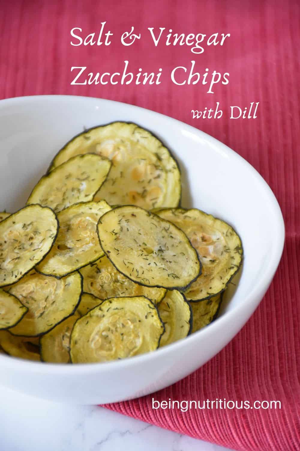 Zucchini chips in a white bowl with a red napkin under it.