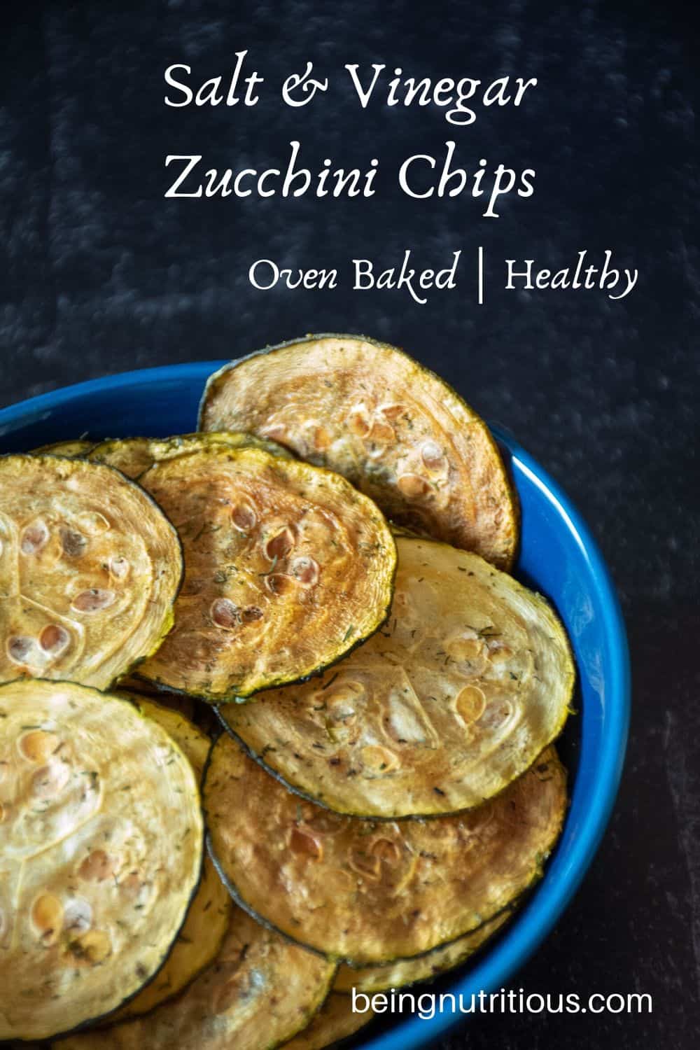 Zucchini chips in a blue bowl in front of dark background.