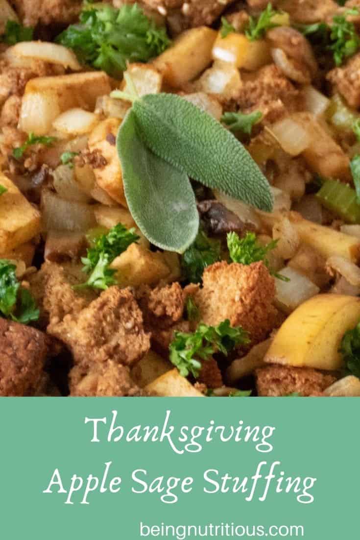 Close up of stuffing, garnished with 2 fresh sage leaves. Text overlay in a mint green rectangle: Thanksgiving apple sage stuffing.