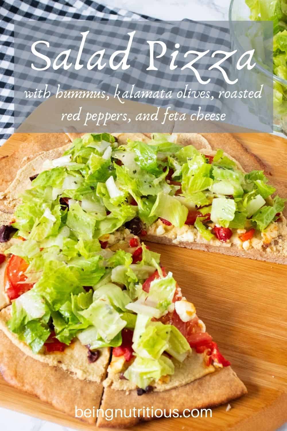 Pizza on a peel, with whole wheat crust, topped with salad. Text overlay: Salad Pizza with hummus, kalamata olives, roasted red peppers, and feta cheese.