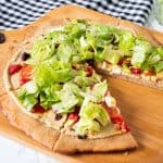 Pizza on a peel, with whole wheat crust, topped with salad.