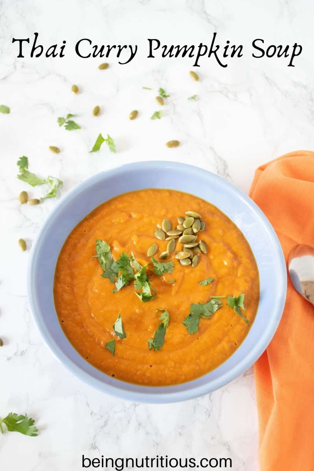 Overhead shot of pumpkin soup in a blue bowl, garnished with cilantro and pepitas. Text overlay: Thai Curry Pumpkin Soup