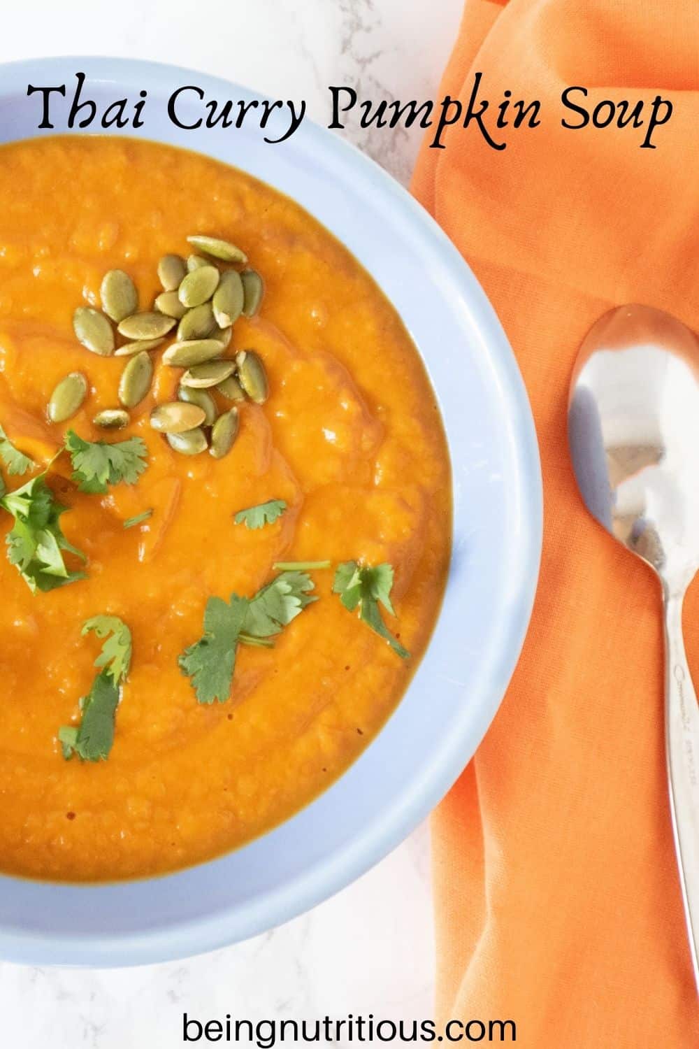 Overhead shot of pumpkin soup in a blue bowl, garnished with cilantro and pepitas. Text overlay: Thai Curry Pumpkin Soup