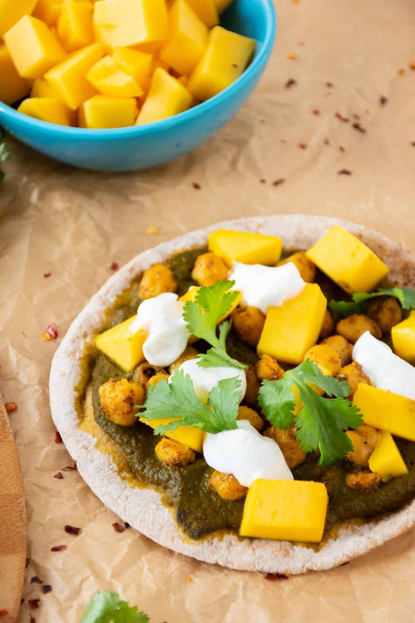 pizza with spinach sauce, chickpeas, and mangoes on mini pitas.