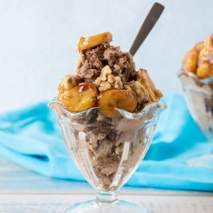 Sundae dish with nice cream topped with caramelized bananas and walnuts