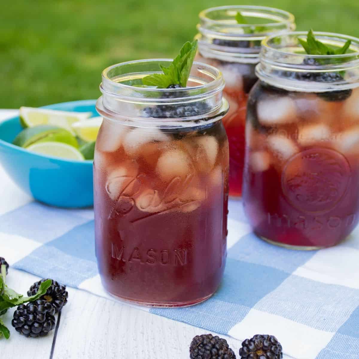Iced tea in Mason jars, with ice, blackberries, and mint.