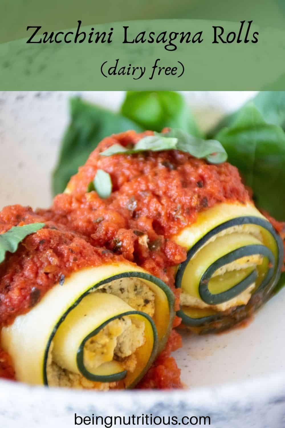 Close up of two zucchini rolls in a bowl. Text overlay: Zucchini Lasagna Rolls; dairy free.