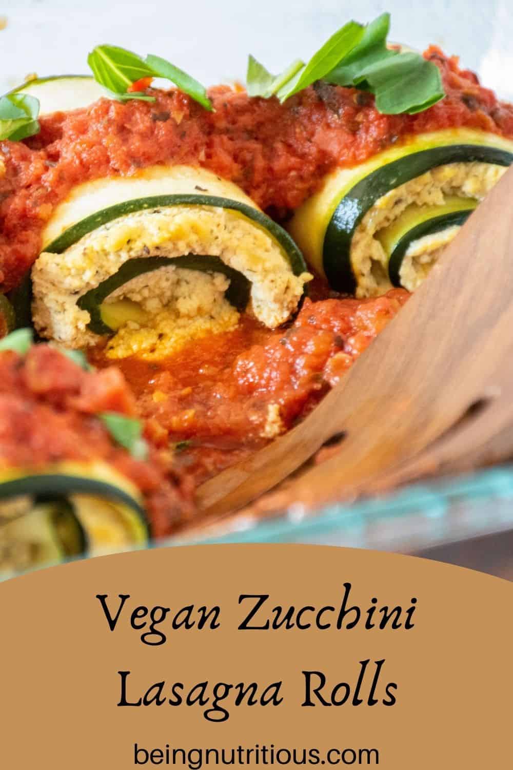 Close up of zucchini rolls in a casserole. Text overlay: Vegan Zucchini Lasagna Rolls.